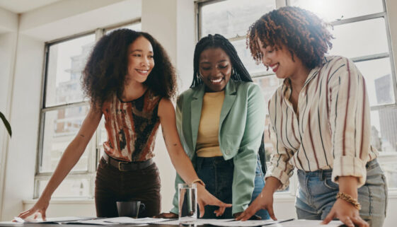 Teamwork, collaboration and planning black women with documents, paperwork or design strategy in office. Business startup, gender equality and marketing ideas of diversity people in workspace meeting